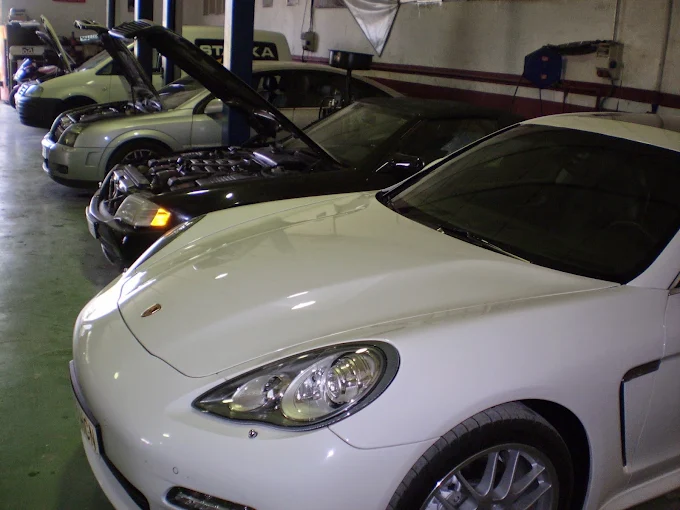 Coches con el capó abierto en reparación dentro del taller Starka Motor