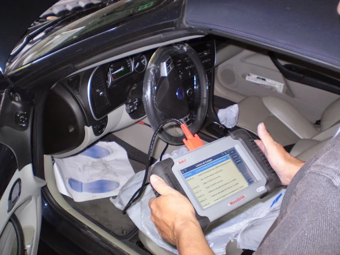 Mecánico leyendo códigos de avería de un coche con una máquina de diagnosis conectada
